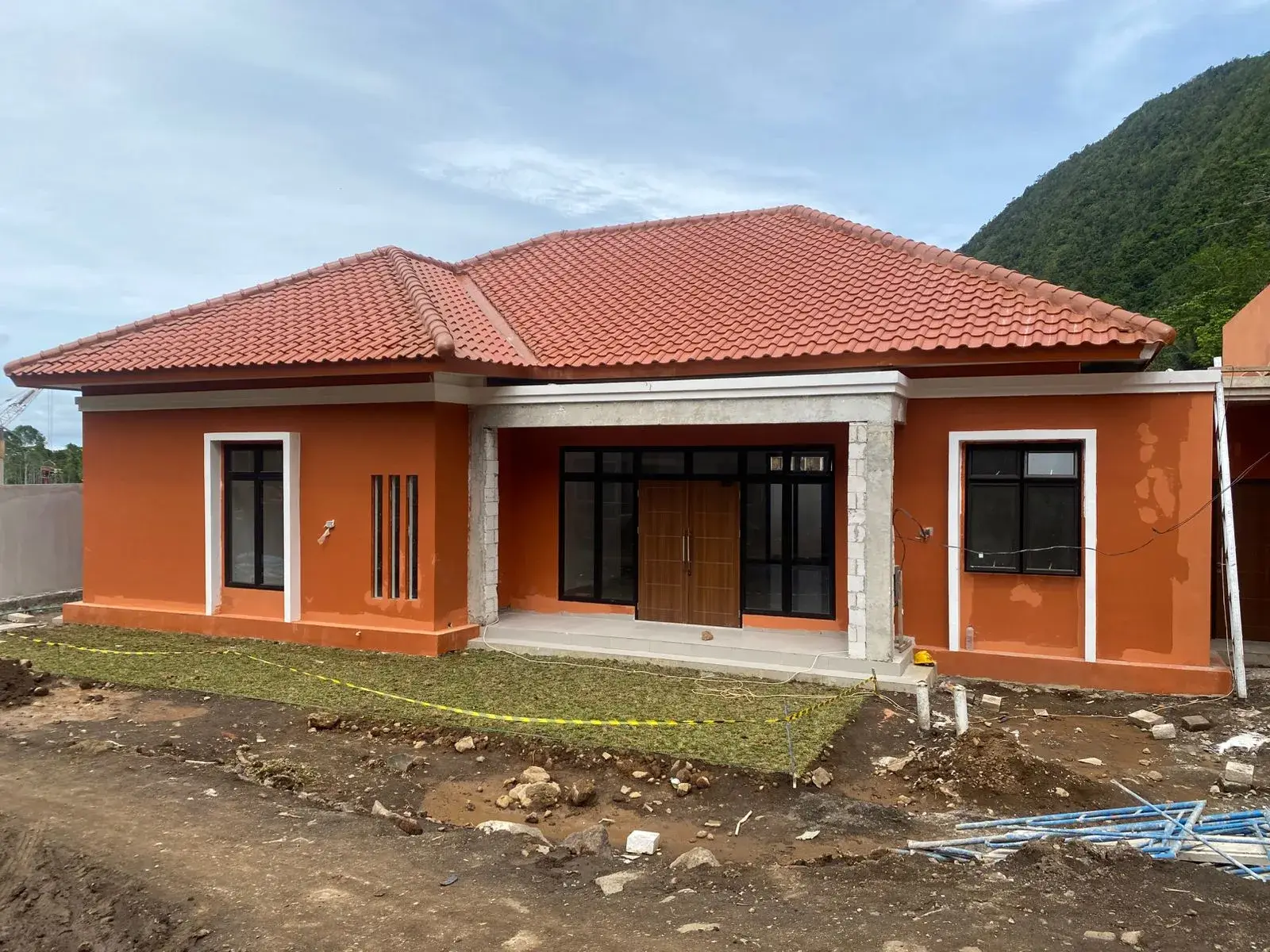 Tampak bangunan SMA Taruna Nusantara Manado dalam tahap pengerjaan dengan pintu utama dan jendela berbingkai gelap.